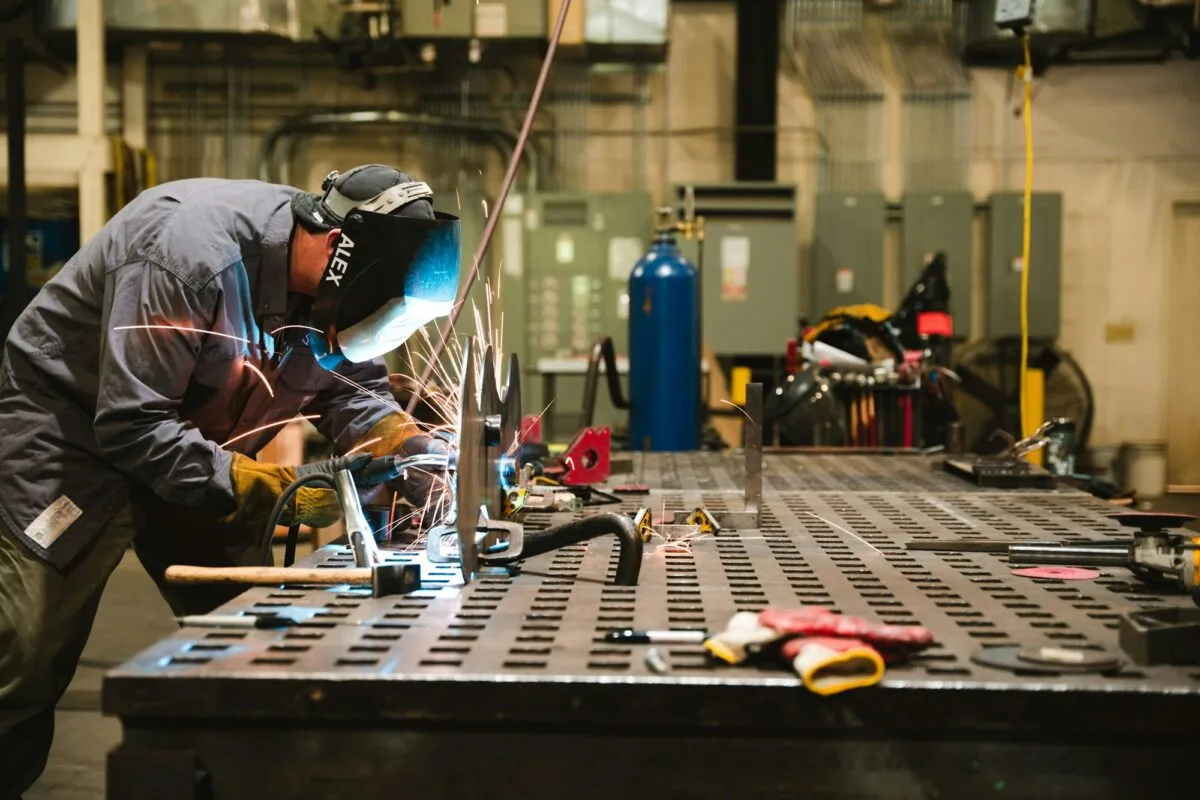 Fabricator welding at a steel workbench